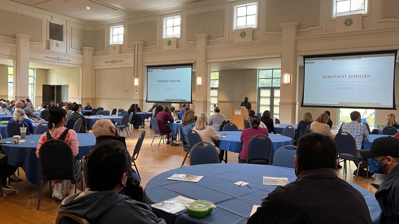 People sitting at round tables watching a presentation.